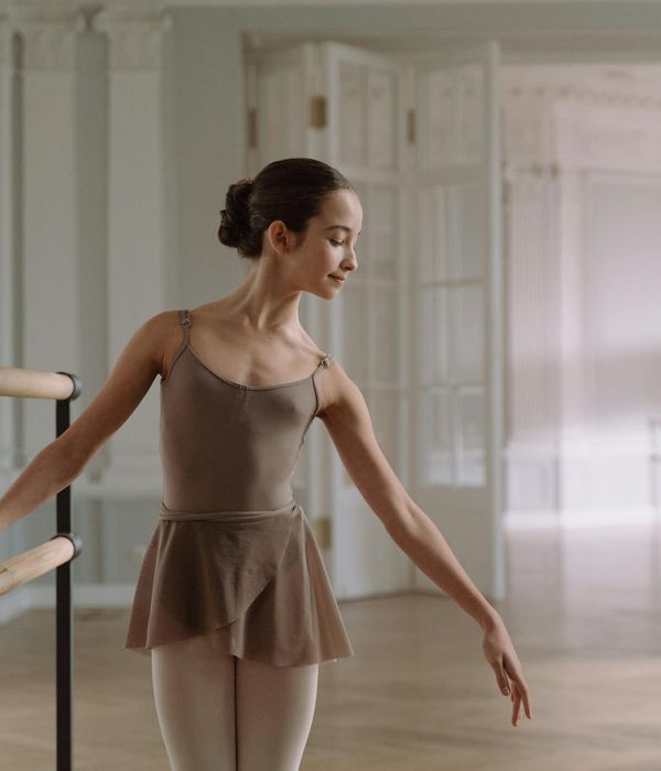 Woman performing a light cardio jump in a minimalist studio.